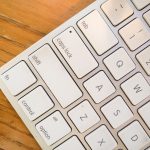 A detailed close-up of a modern computer keyboard on a wooden desk. — Branding Technology is the Same But Different