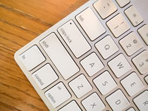 A detailed close-up of a modern computer keyboard on a wooden desk. — Branding Technology is the Same But Different