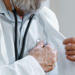 Close-up of a doctor adjusting a stethoscope while in a medical consultation. — CompareMedicareAdvantagePlans.org Helping You