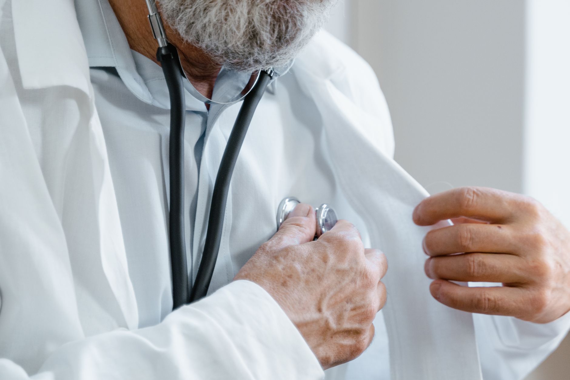 Close-up of a doctor adjusting a stethoscope while in a medical consultation. — CompareMedicareAdvantagePlans.org Helping You