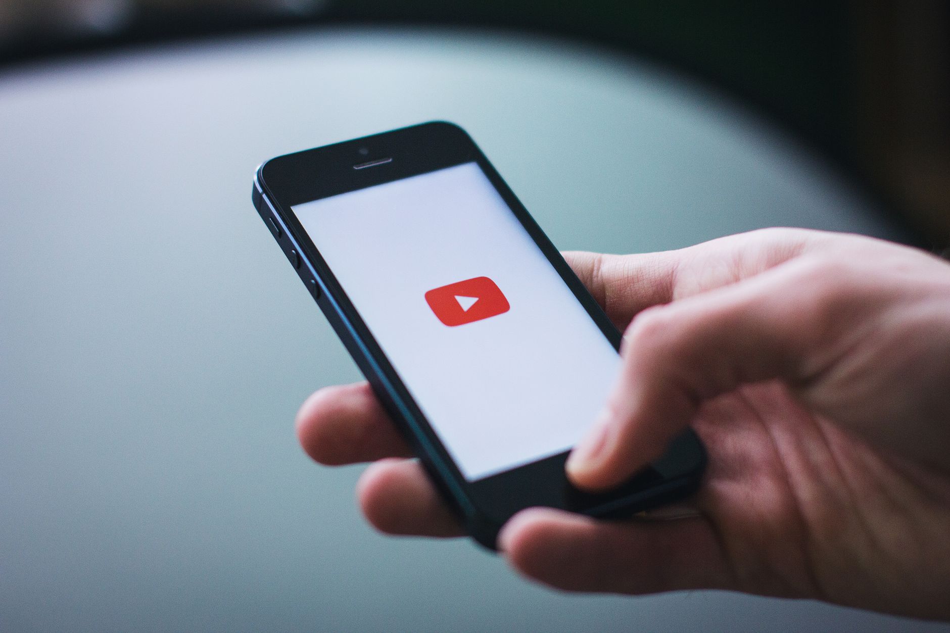 Close-up of a hand holding a smartphone displaying the YouTube app on the screen. — Experience the Thrill of Live Premier Lea