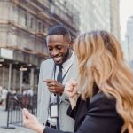 Two business professionals engage in lively conversation on an urban street, sharing insights. — Generate Genuine Interest wi