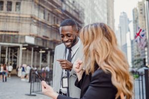 Two business professionals engage in lively conversation on an urban street, sharing insights. — Generate Genuine Interest wi