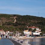A beautiful coastal promenade in Foça, İzmir with a hillside backdrop, perfect for a relaxing stroll. — How can you save up y