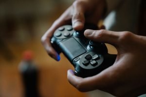 Crop anonymous male pressing buttons on console controller while playing video game in house on blurred background — Learning