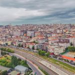 Aerial view of dense urban architecture with roads and greenery under cloudy skies. — Legitimate Sources for Purchasing a Sta