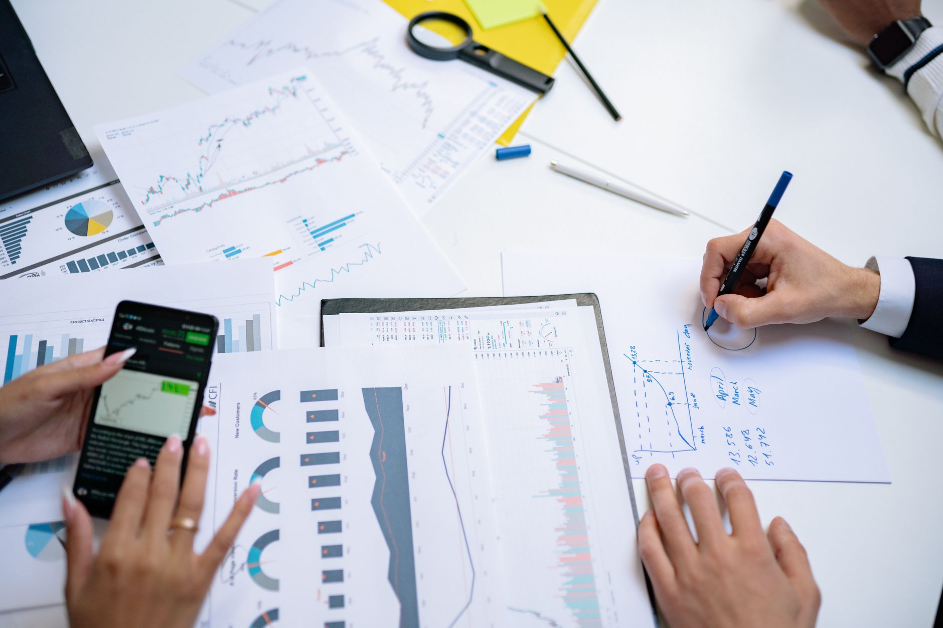 Colleagues collaborating on financial charts and graphs using mobile and paper documents in the office. — Mastering Private M