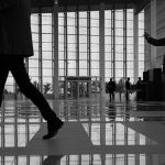 Business professionals walk through a modern, glass-paneled indoor space. — Navigating the World of Online Testosterone Presc