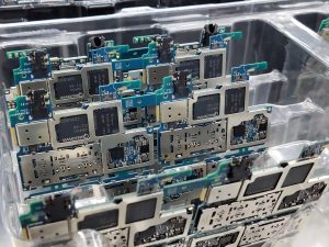 From above of circuit boards of modern smartphones placed in plastic box in electronics factory — Online Electronics Training