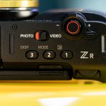 Detailed close-up of a camera's control interface featuring buttons and dials, emphasizing its design and functionality. — SM