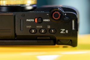 Detailed close-up of a camera's control interface featuring buttons and dials, emphasizing its design and functionality. — SM
