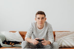 Teen boy intensely focused on video games at home, relaxing on a couch. — The Benefits Of Gaming At Direct Joker123 Website