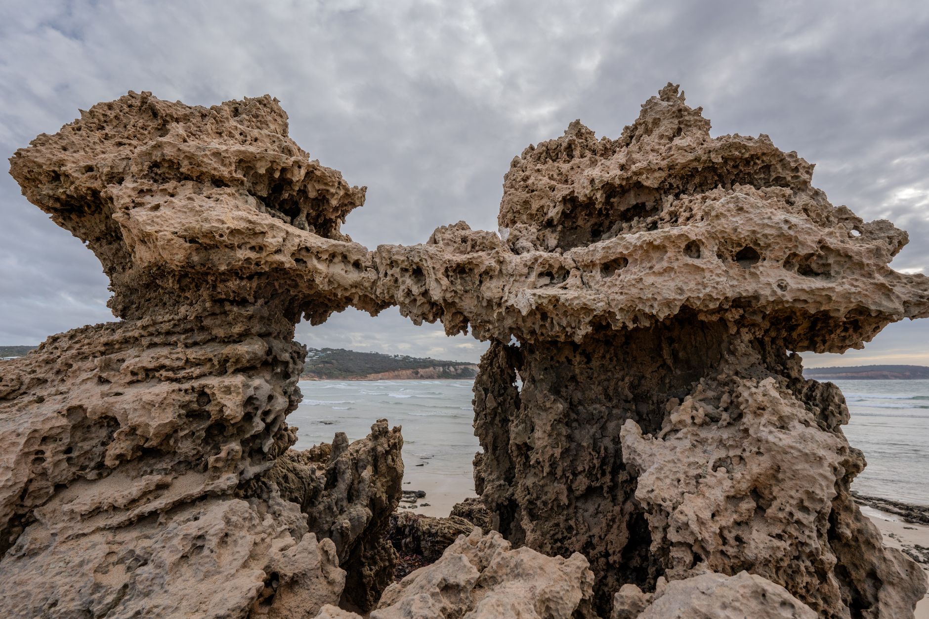 A striking coastal rock formation displaying natural erosion against a cloudy backdrop by the sea. — The Benefits of Using Ma