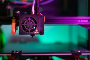 Vibrant close-up of a 3D printer component in action with colorful lighting creating a modern industrial vibe. — The Future o