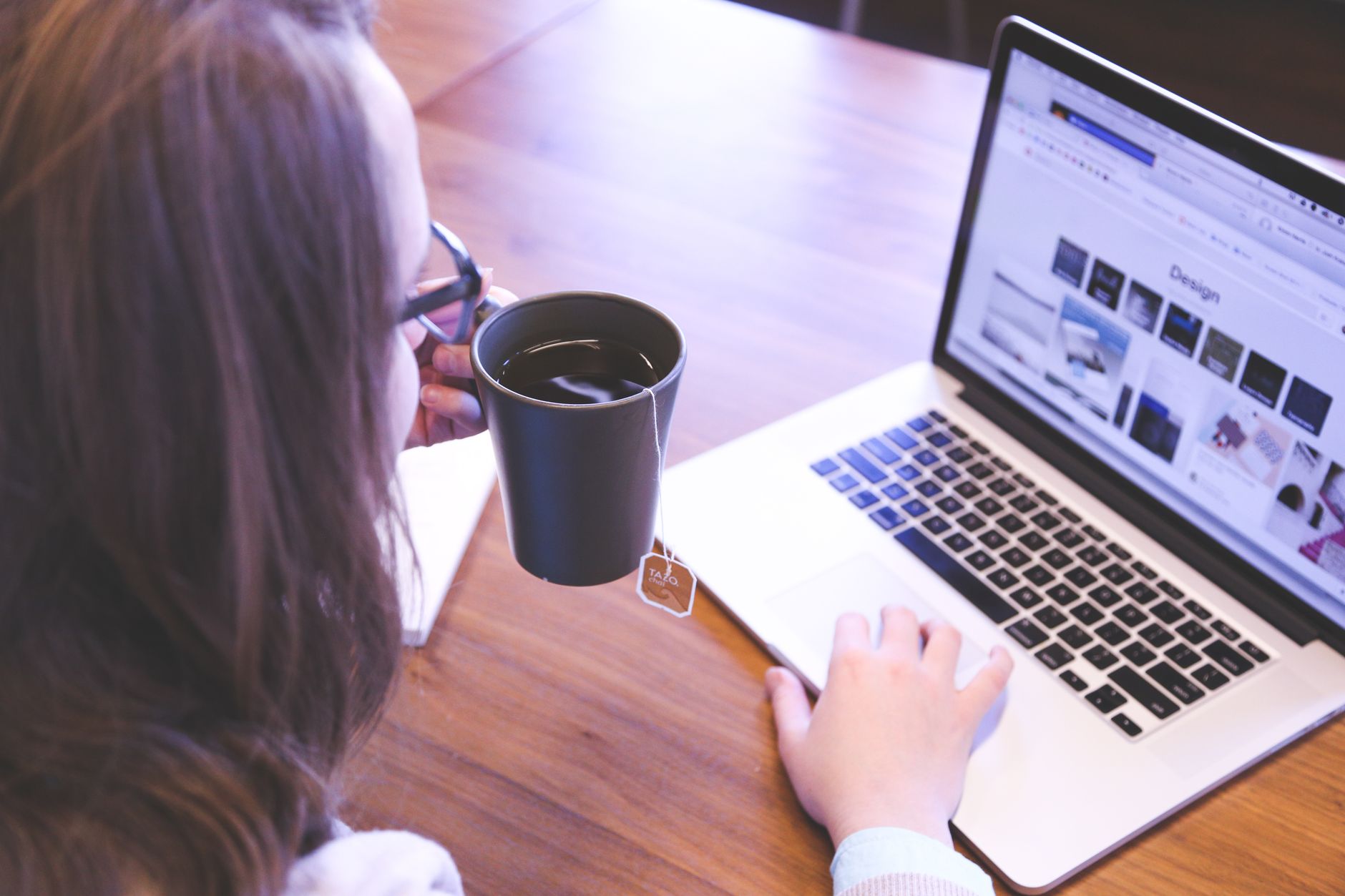 A woman enjoys coffee while browsing the web on a laptop at a home office desk. — The Lowdown on 4G Wireless Internet