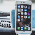 Close-up of a smartphone mounted on a car dashboard showing home screen with apps. — The Promise of Technology is Intangible