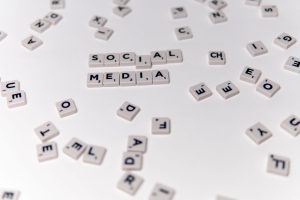 White Scrabble tiles forming the phrase 'social media' on a scattered background. — The Pros and Cons of Viewing Instagram St