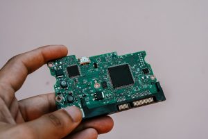 Close-up image of a hand holding a circuit board from a hard drive, showcasing electronic technology. — Top 10 Mistakes Busin