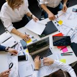 A group of colleagues working around a table, reviewing documents and using laptops and tablets. — What Makes The Best SEO Co
