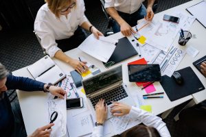 A group of colleagues working around a table, reviewing documents and using laptops and tablets. — What Makes The Best SEO Co