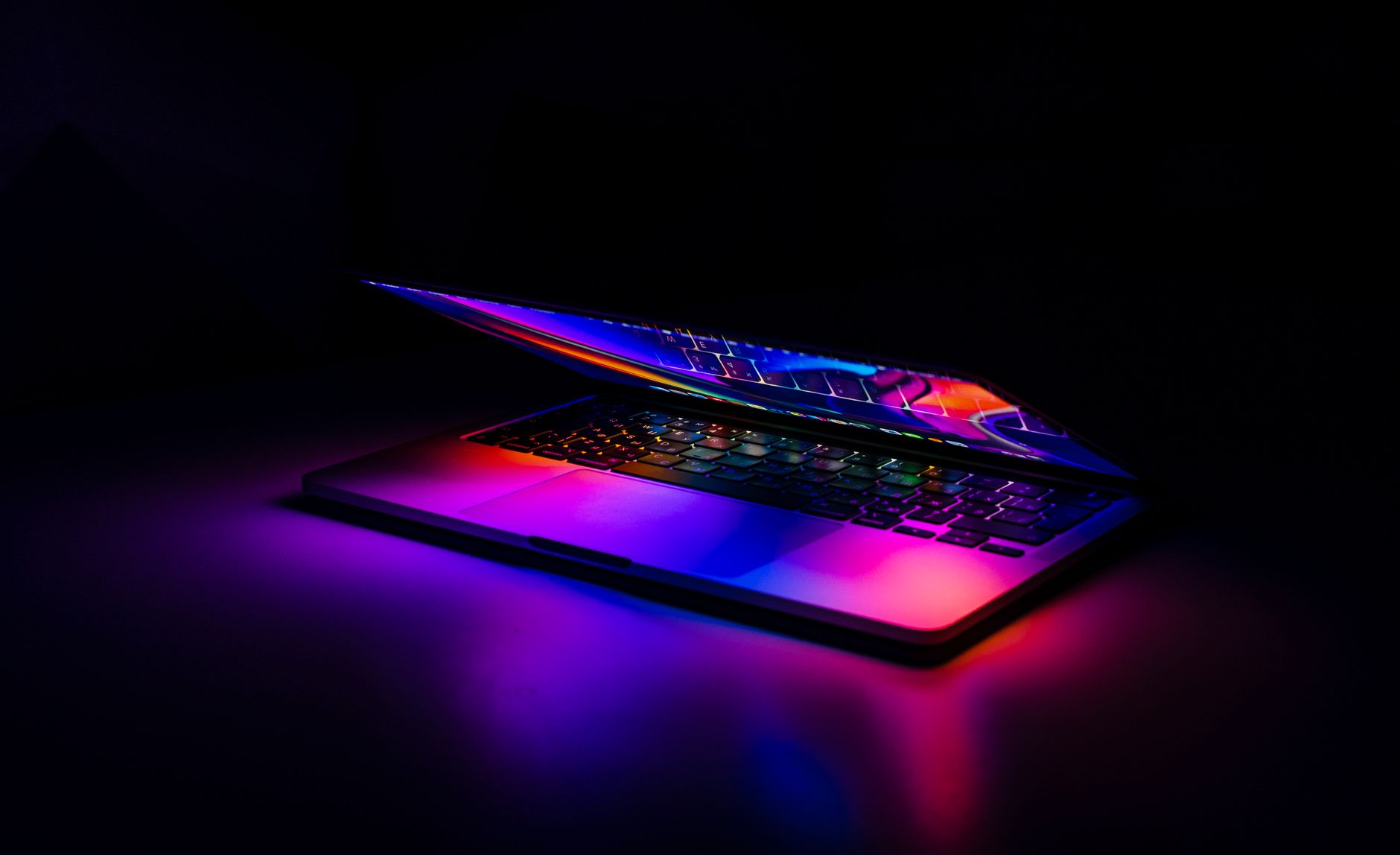 A partially closed MacBook with vibrant, colorful light reflections on a dark background. — What To Know About The Fibonacci