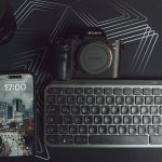 Elegant workspace setup featuring camera, smartphone, and keyboard on a geometric background. — Wholesale Electronics - Endle