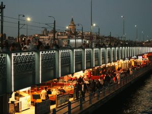 Night view of Galata Bridge bustling with people and distant Galata Tower in Istanbul. — Why Boxing in Pipes is a Homeowner's
